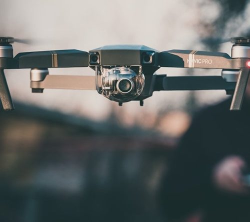 Fliegende Drohne mit Drohnenpilot im Hintergrund