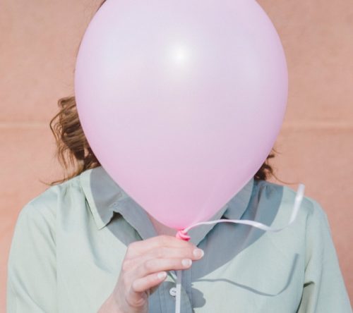 Frau mit Ballon vor dem Gesicht
