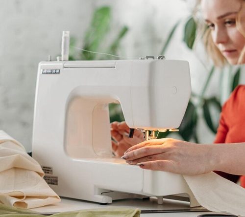 Frau mit rotem Pullover an Nähmaschine