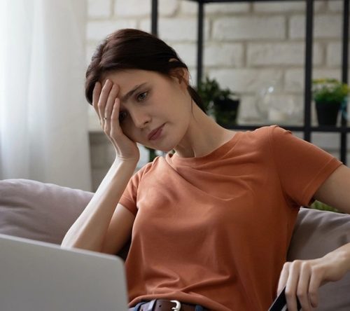 Frau sitzt verzweifelt vor dem Laptop