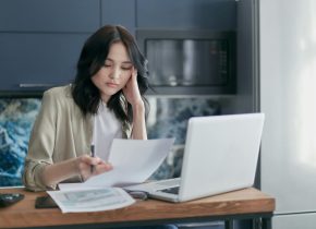 Frau mit Zettel am Laptop