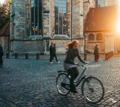 magazin_hero_frau_mit_rad_vor_kirche