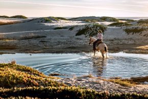 Frau reitet durch Wasser